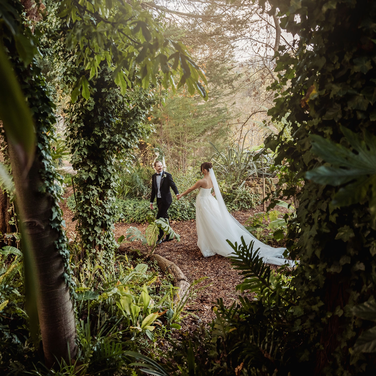 the manor wedding - crystal & mackenzie 67 Bride and groom woodland wedding portrait in lush garden with flowing veil.