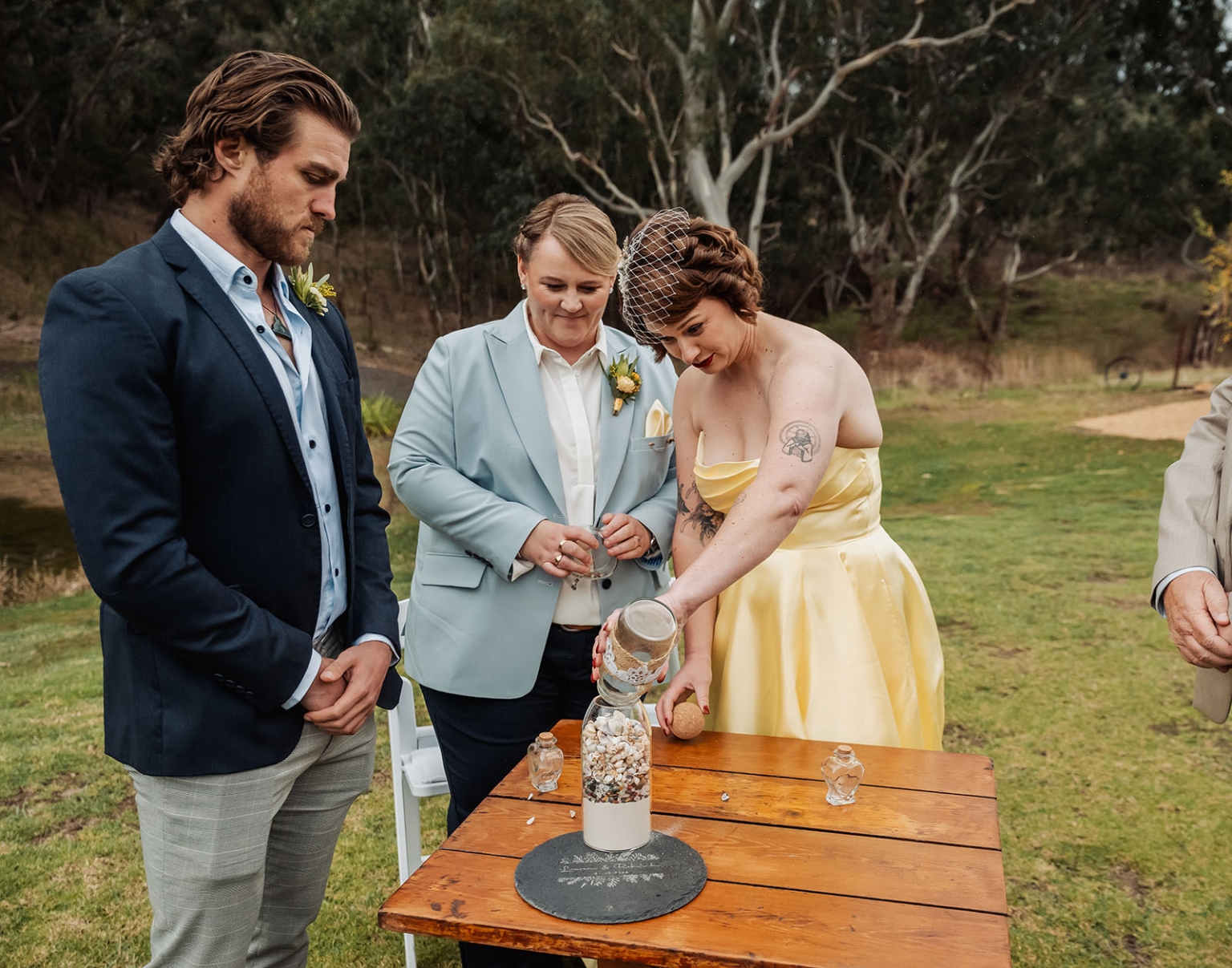 tiny house on the prairie wedding - lauren & bek 26 Woodland wedding unity sand ceremony with bride, groom, and officiant at rustic table.