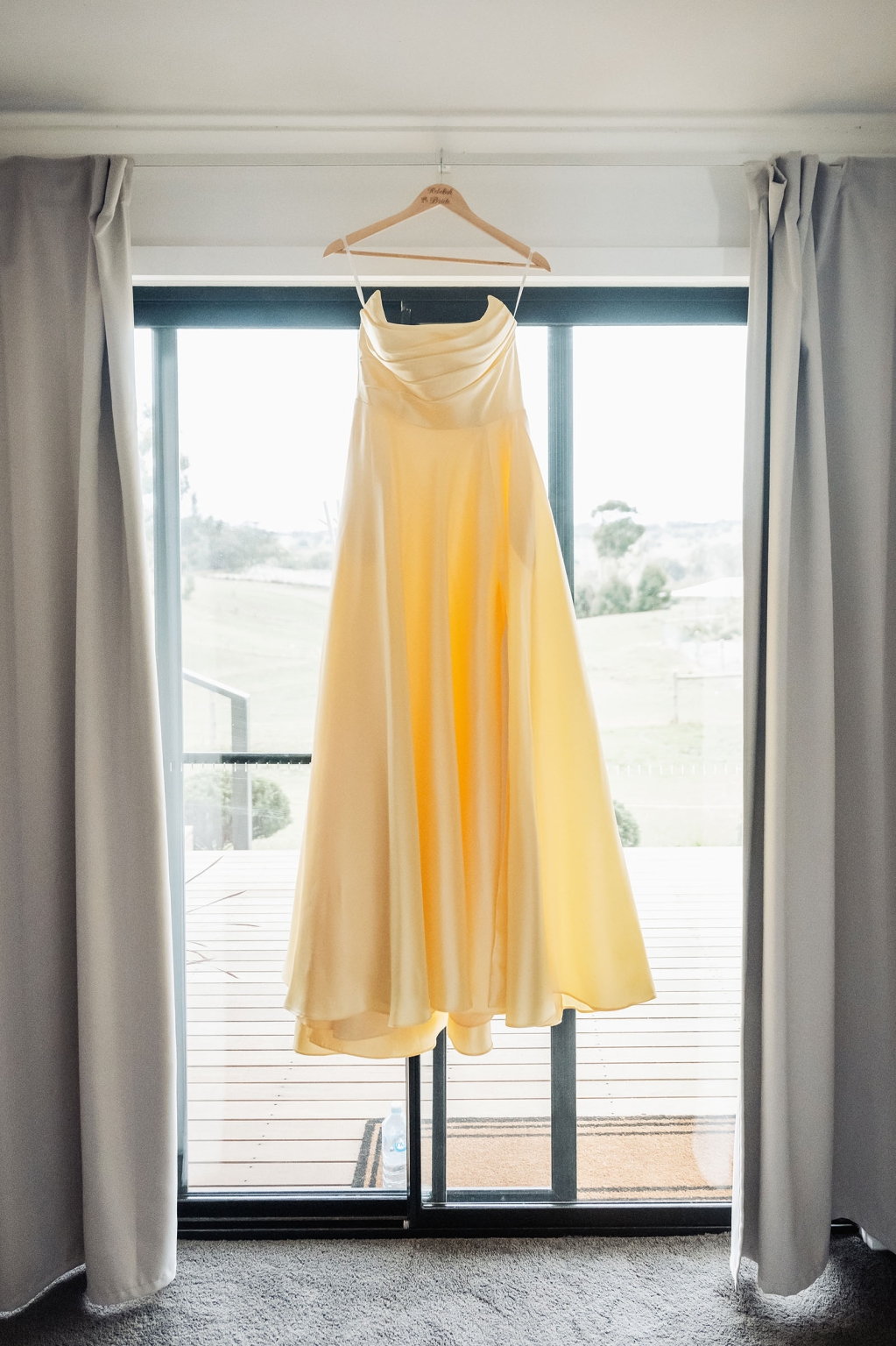 tiny house on the prairie wedding - lauren & bek 4 Elegant yellow bridesmaid dress hanging by sunlit sliding glass door.