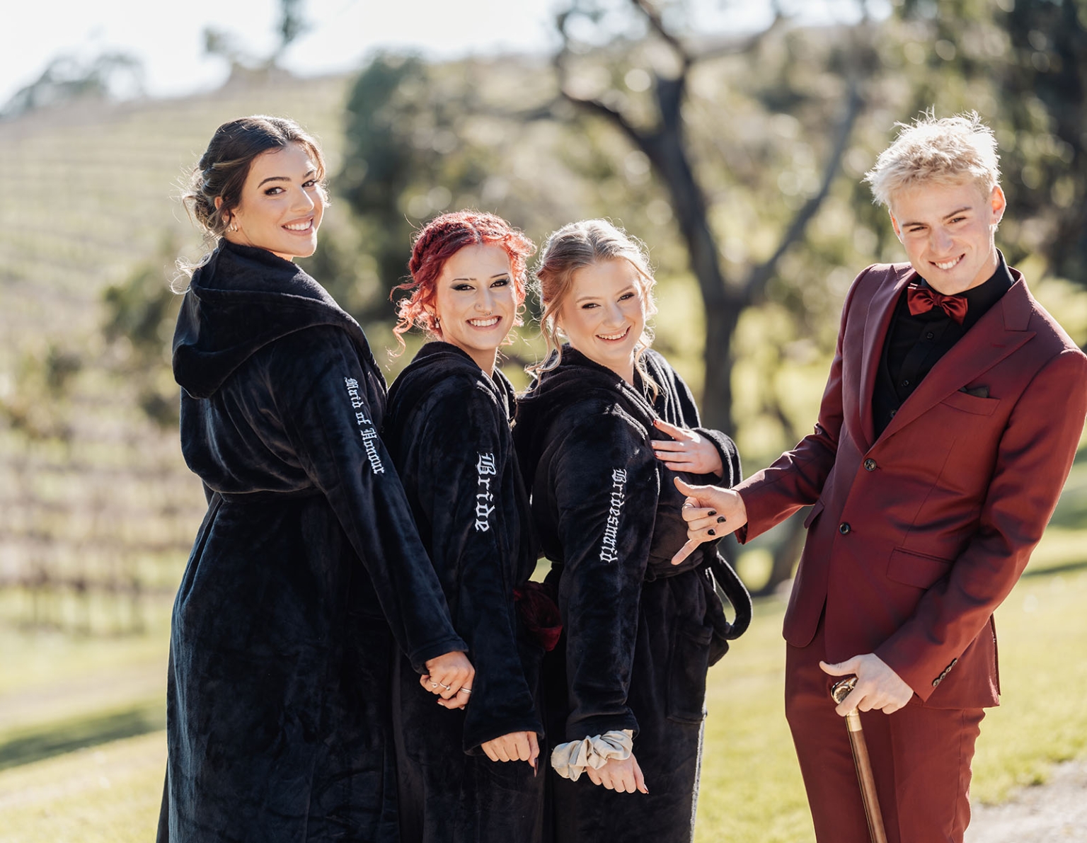 kuitpo hall wedding - courtney & jarrod 204 Bridal party in black robes with groom in burgundy suit outdoors.