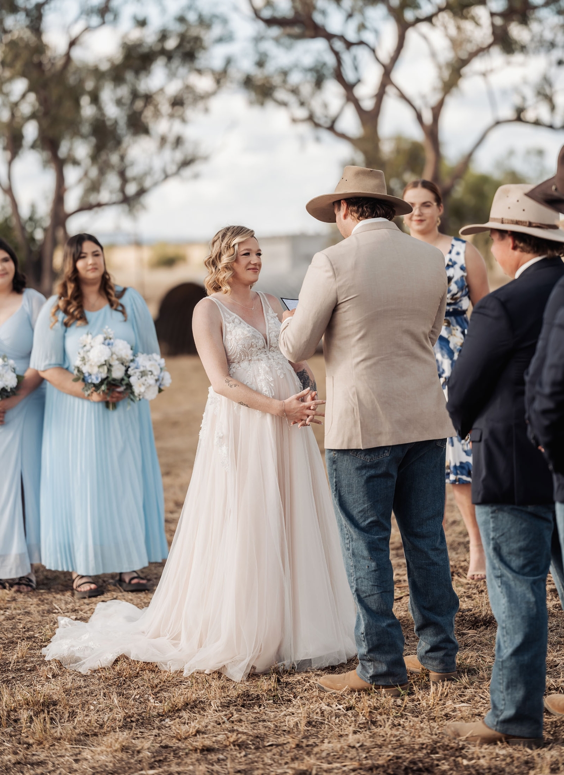 capella wedding photography – caitlin & adam’s farm wedding 143 Caitlin and Adam holding hands during their outdoor farm wedding ceremony in Capella, with bridesmaids and guests nearby.