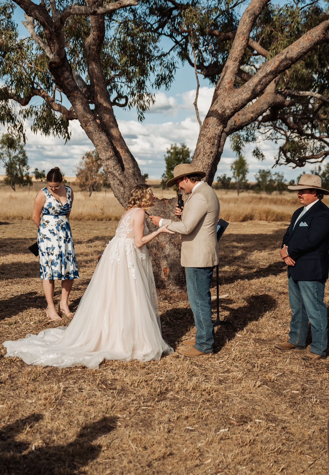 capella wedding photography – caitlin & adam’s farm wedding 145 Caitlin and Adam stand beneath a large gum tree during their outdoor farm wedding ceremony in Capella.