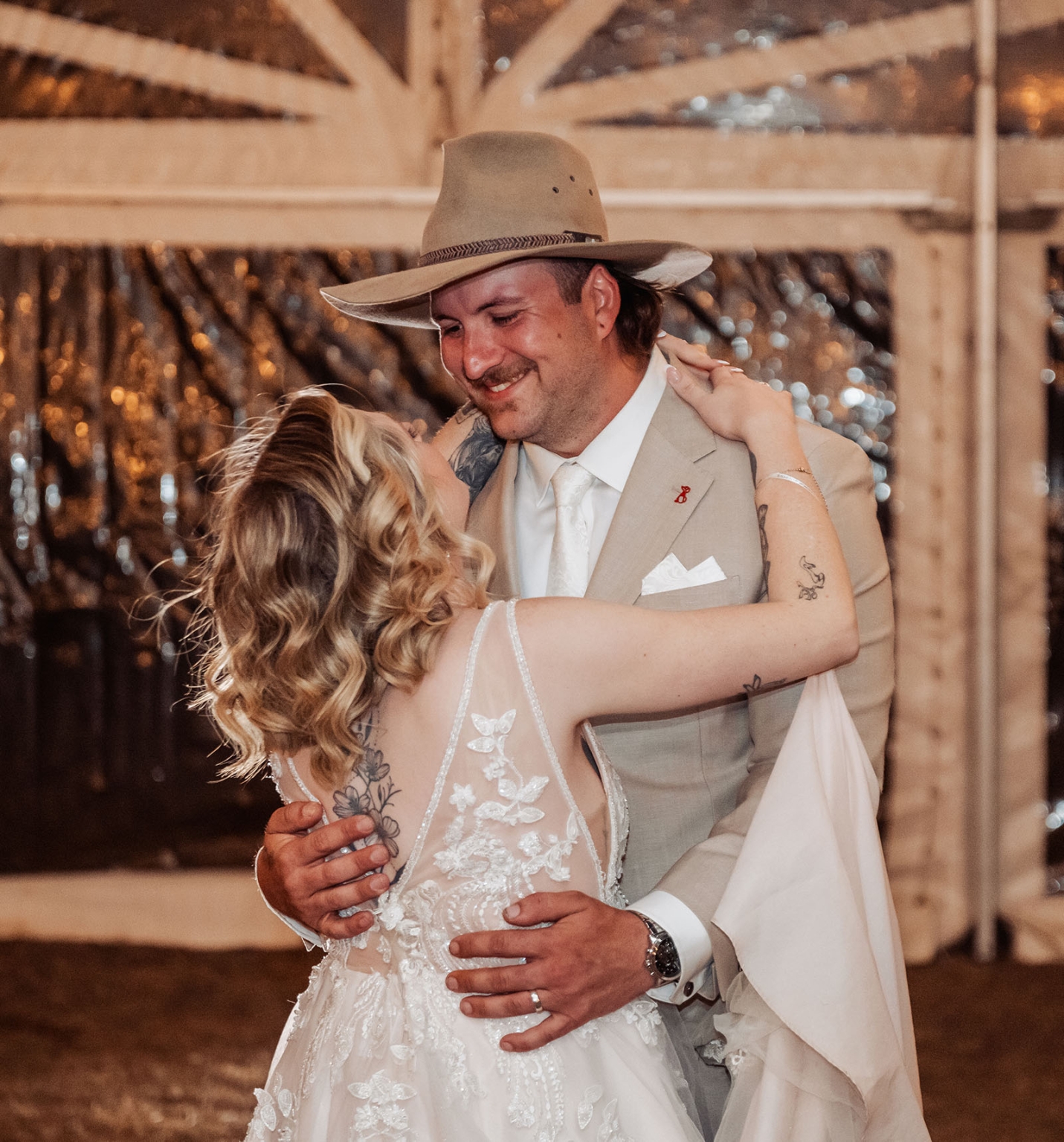 capella wedding photography – caitlin & adam’s farm wedding 178 Caitlin and Adam dancing together at their farm wedding, with Adam wearing a wide-brimmed hat and beige suit.