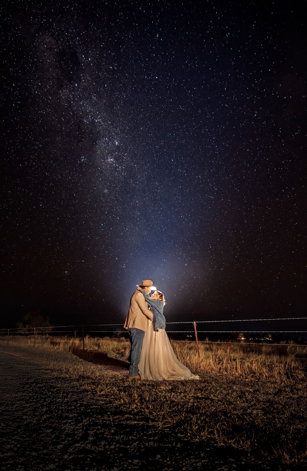 capella wedding photography – caitlin & adam’s farm wedding 187 Caitlin and Adam embracing beside a farm fence beneath the Milky Way at night in Capella, Queensland.