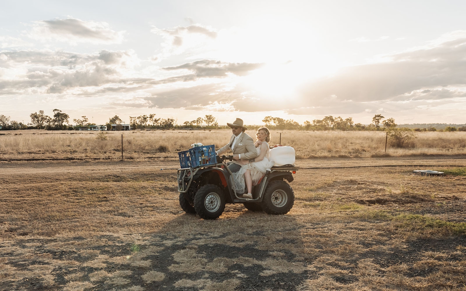 capella wedding photography – caitlin & adam’s farm wedding 163 Caitlin and Adam riding a quad bike across a dry farm paddock at sunset after their Capella wedding