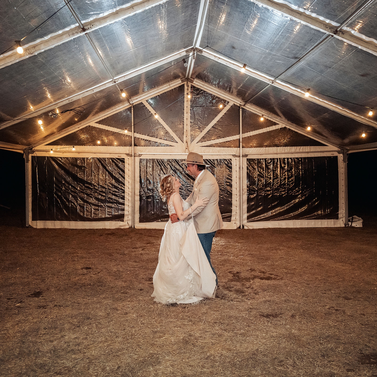 capella wedding photography – caitlin & adam’s farm wedding 177 Caitlin and Adam dancing beneath string lights outside a clear-roofed wedding marquee at their Capella farm wedding.