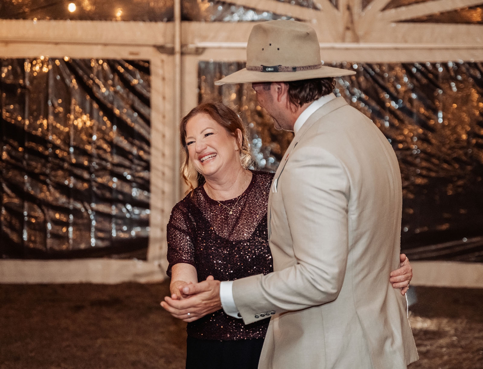 capella wedding photography – caitlin & adam’s farm wedding 179 Wedding guests dancing together beneath string lights at a farm reception in Capella