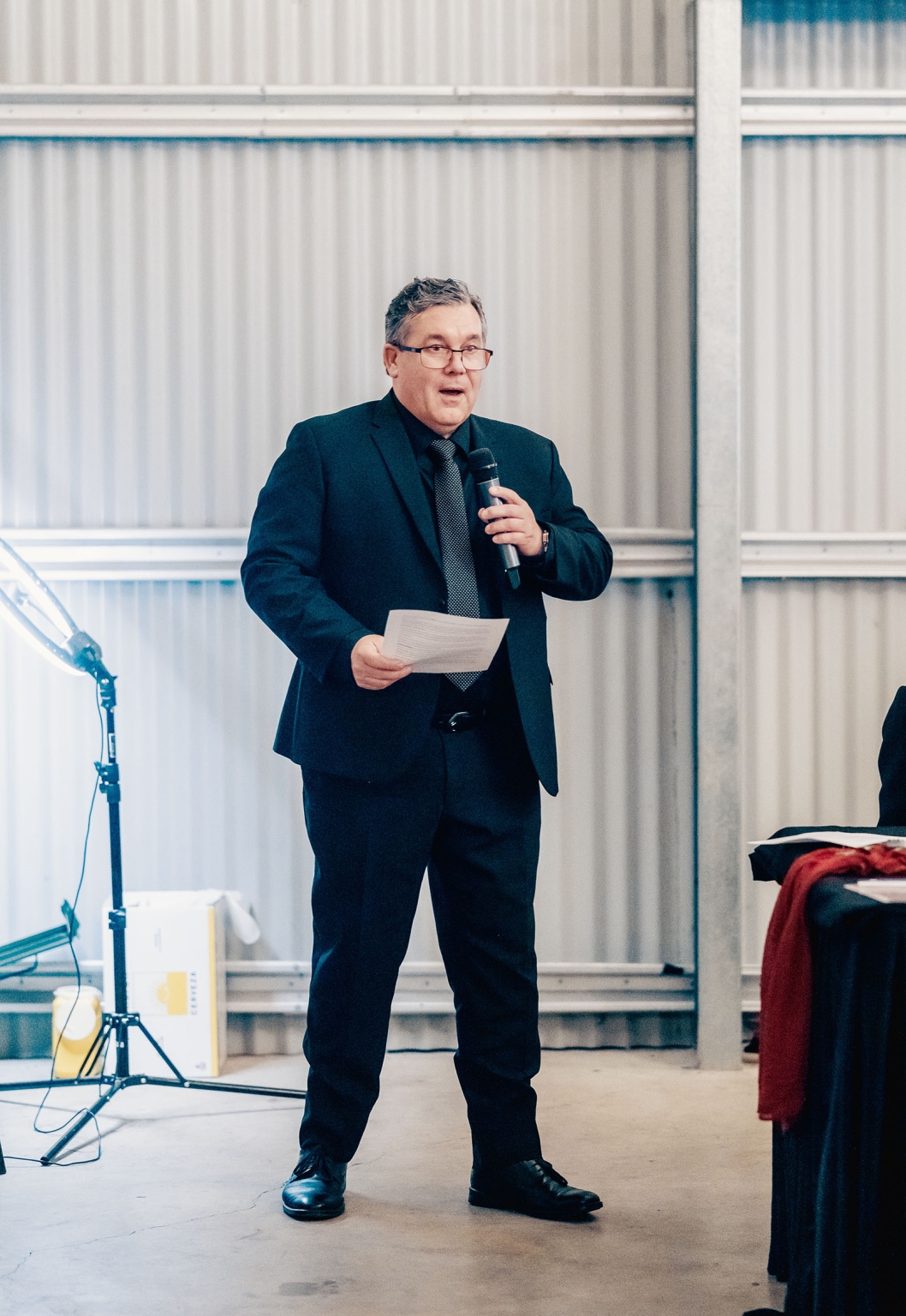 kuitpo hall wedding - courtney & jarrod 264 Formal speaker presenting with microphone in industrial event venue.