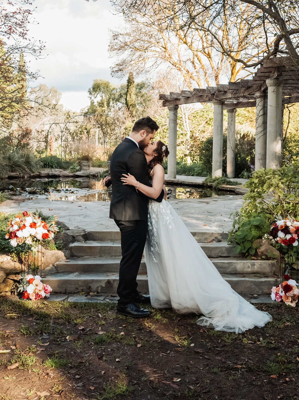 wedding at al-ru farm – teresa & thomas 25 Bride and groom kiss during romantic outdoor garden wedding with floral arrangements.