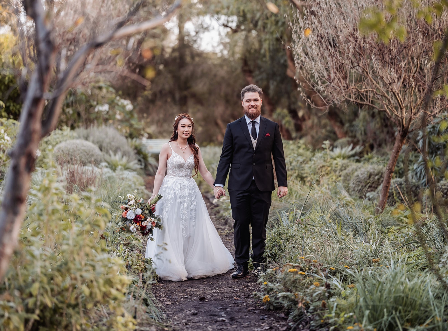 wedding at al-ru farm – teresa & thomas 16 Romantic garden wedding couple walking hand in hand on a lush woodland path.