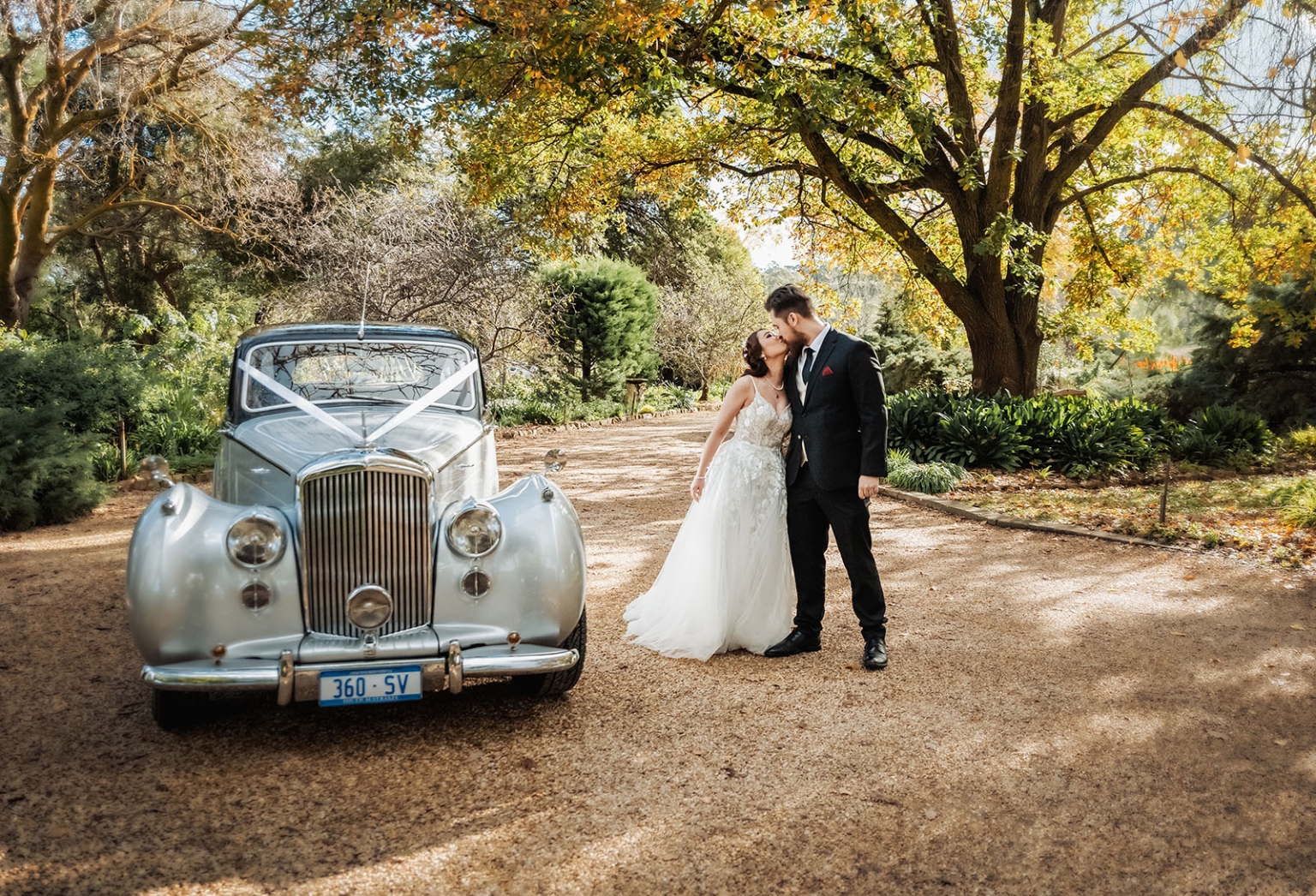 wedding at al-ru farm – teresa & thomas 3 Bride and groom kissing beside vintage wedding car in garden.