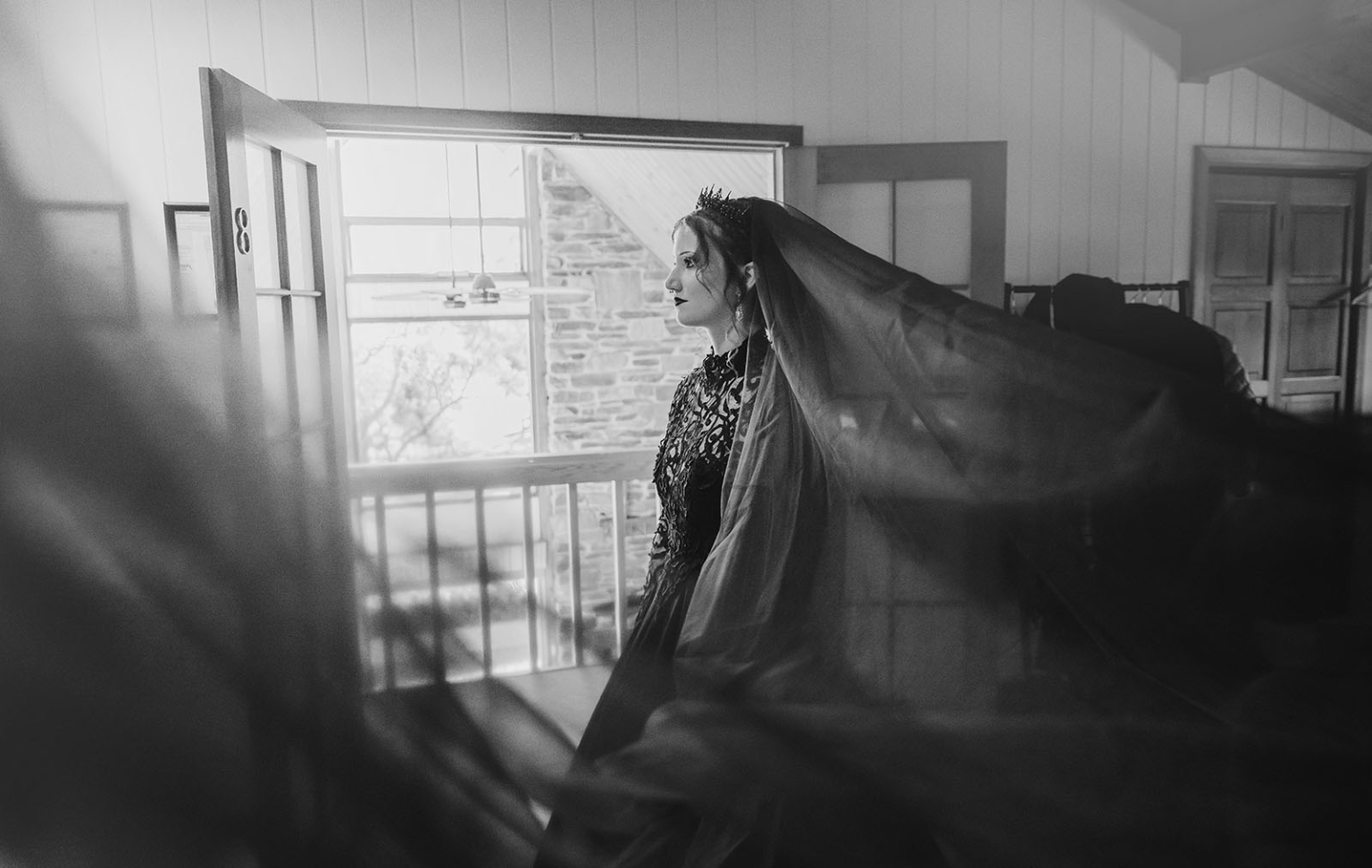 kuitpo hall wedding - courtney & jarrod 210 Gothic bride in ornate gown and veil by sunlit doorway.