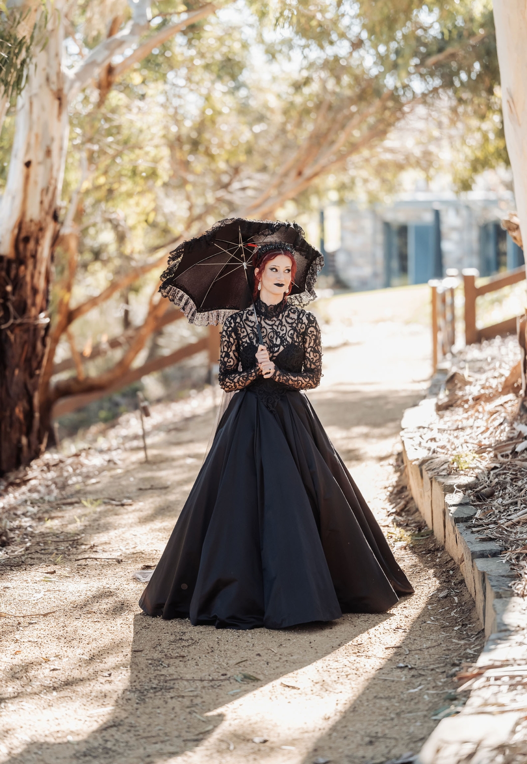 kuitpo hall wedding - courtney & jarrod 216 Gothic woman in black Victorian dress holding parasol on sunlit woodland path.