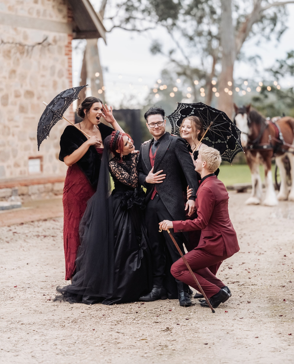 kuitpo hall wedding - courtney & jarrod 234 Gothic formal wedding party portrait with lace parasols, burgundy attire, and horses.