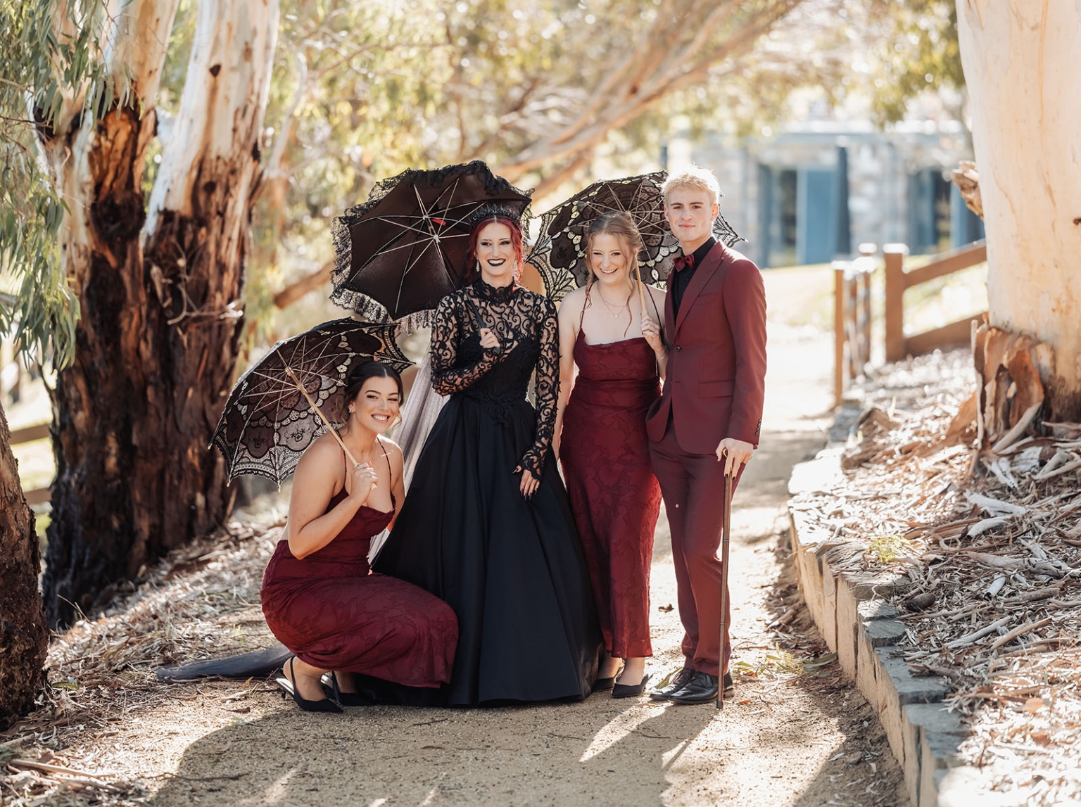kuitpo hall wedding - courtney & jarrod 215 Gothic formal group portrait with burgundy outfits and black lace parasols in wooded setting.