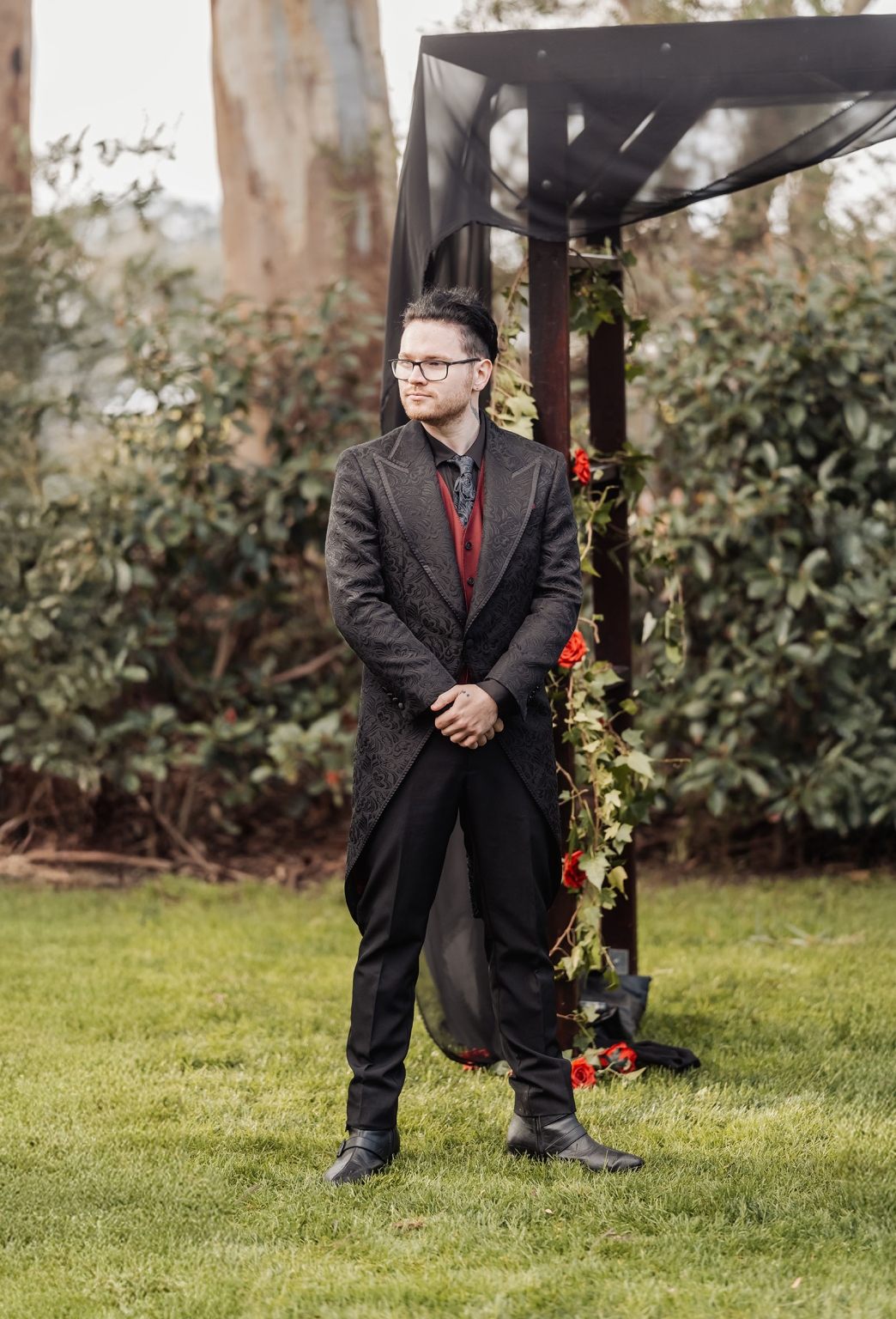 kuitpo hall wedding - courtney & jarrod 221 Gothic formal portrait of man under black garden arch with red roses.
