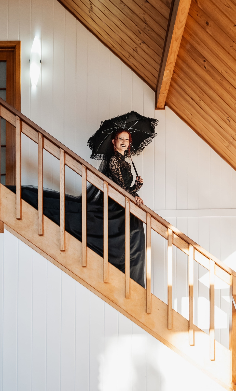 kuitpo hall wedding - courtney & jarrod 212 Gothic woman in black lace dress holding parasol on wooden staircase.