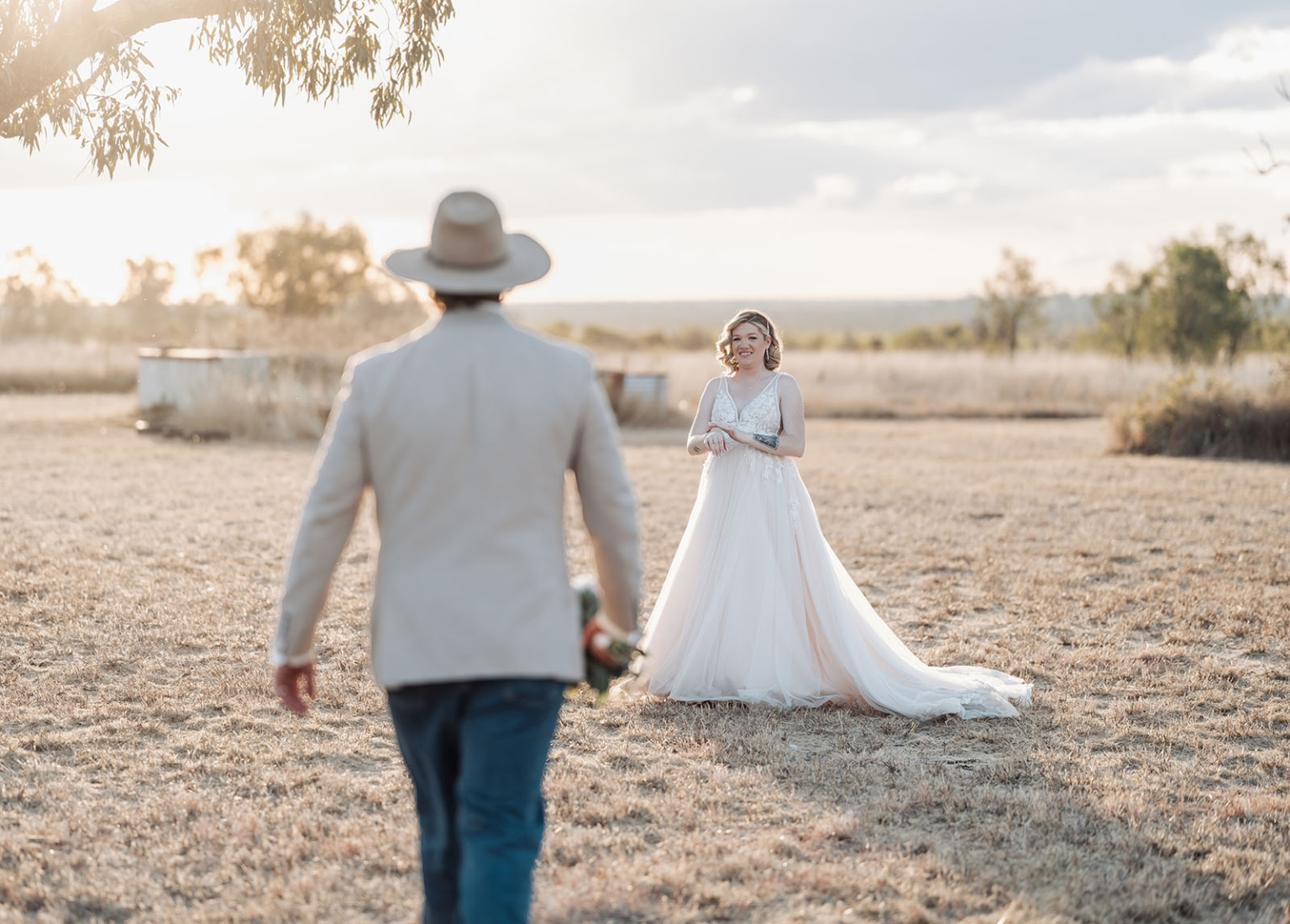capella wedding photography – caitlin & adam’s farm wedding 164 Groom in a cowboy hat walking towards his bride in a sunlit paddock at their Capella farm wedding