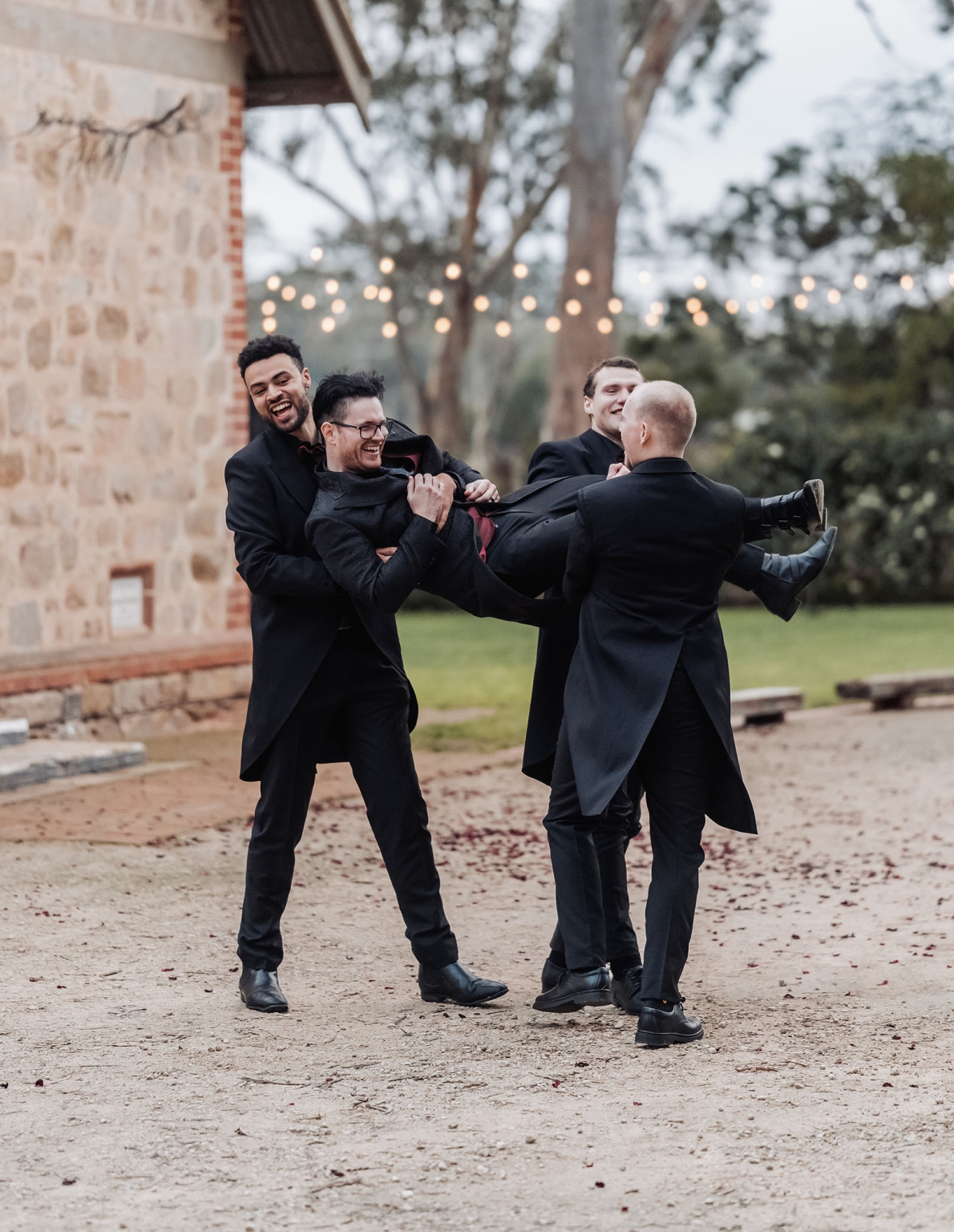 kuitpo hall wedding - courtney & jarrod 236 Groomsmen carrying laughing groom at rustic outdoor wedding celebration.