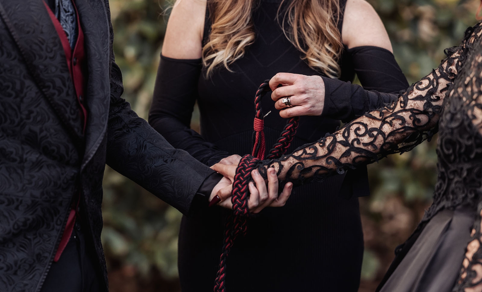 kuitpo hall wedding - courtney & jarrod 229 Gothic handfasting ceremony with braided red and black cord binding hands.