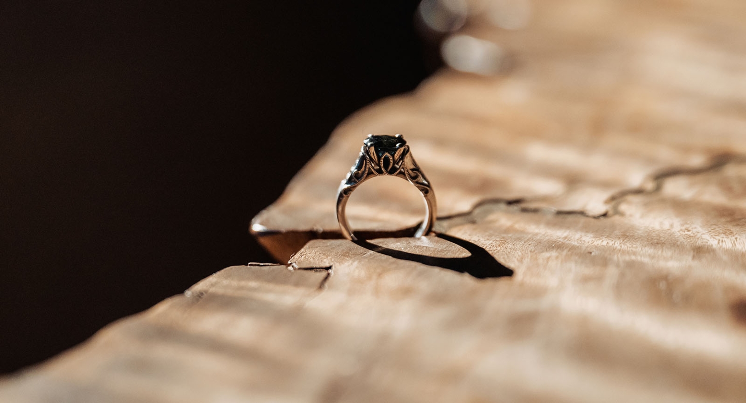 kuitpo hall wedding - courtney & jarrod 203 Ornate gemstone ring on rustic wood with warm vintage lighting.