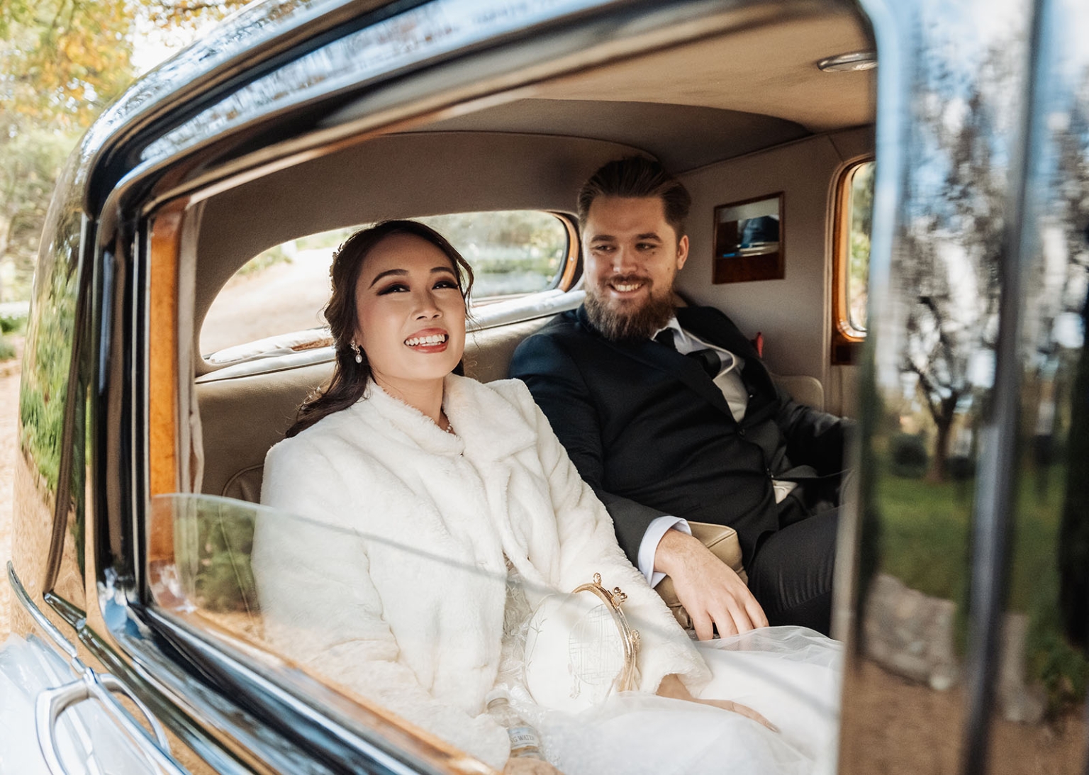 wedding at al-ru farm – teresa & thomas 1 Happy wedding couple in vintage car, bride in white fur coat smiling.