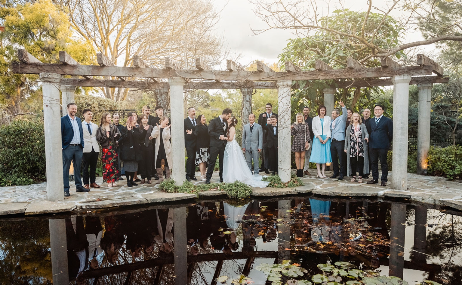wedding at al-ru farm – teresa & thomas 28 Wedding party celebrating under garden pergola with pond reflection.