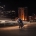 Couple dancing together on the Adelaide riverbank at night, with illuminated city buildings behind them