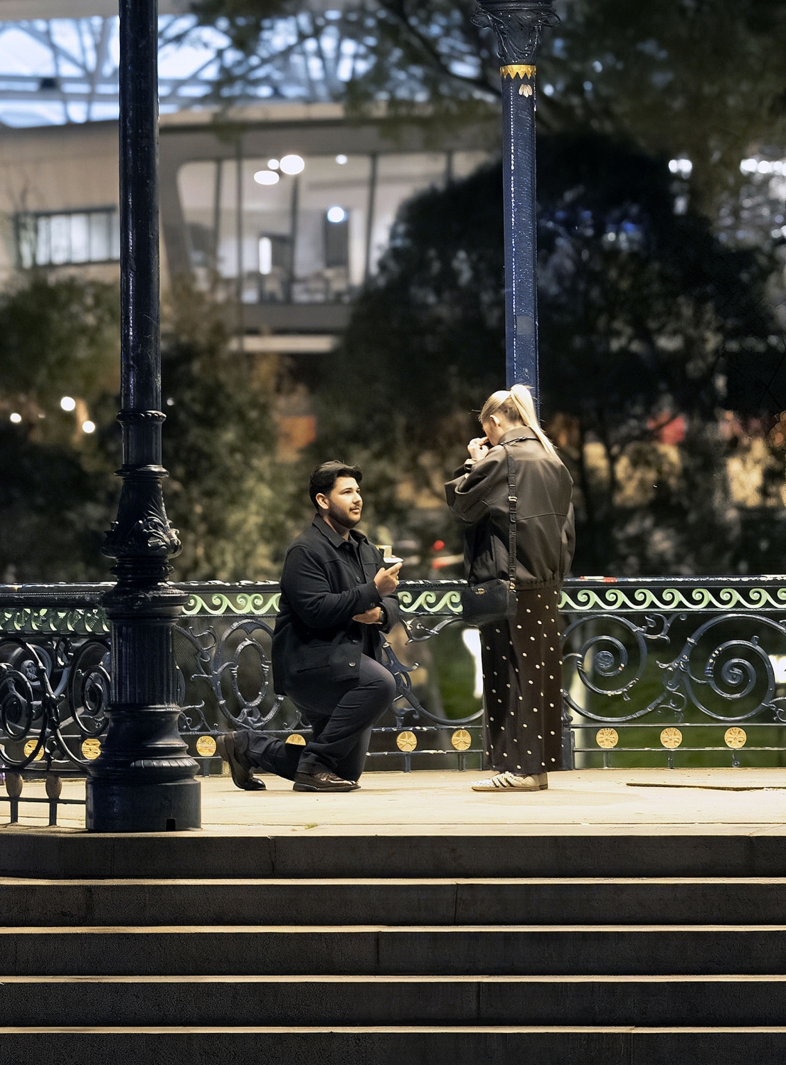 elder park rotunda proposal - lauren & enrique 2 Enrique kneels with a ring box as Lauren reacts on the Elder Park Rotunda in Adelaide.
