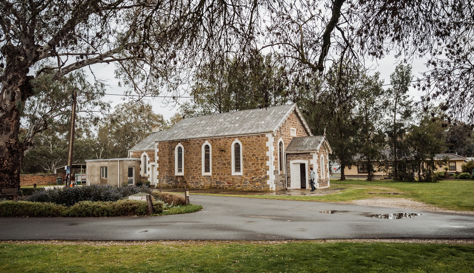 keyneton soldier's memorial hall wedding - lara & simon 2 Stone church with arched windows beneath tall gum trees in Keyneton