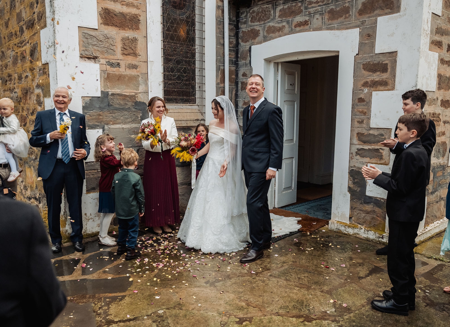 keyneton soldier's memorial hall wedding - lara & simon 16 Lara and Simon leaving the stone church as wedding guests throw flower petals
