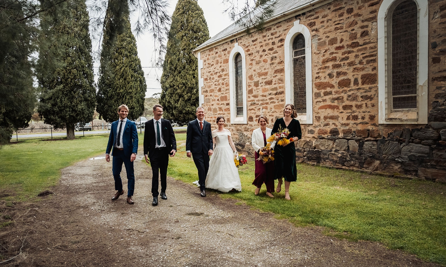 keyneton soldier's memorial hall wedding - lara & simon 23 Lara and Simon walking with their wedding party beside the stone church at Keyneton Soldier's Memorial Hall