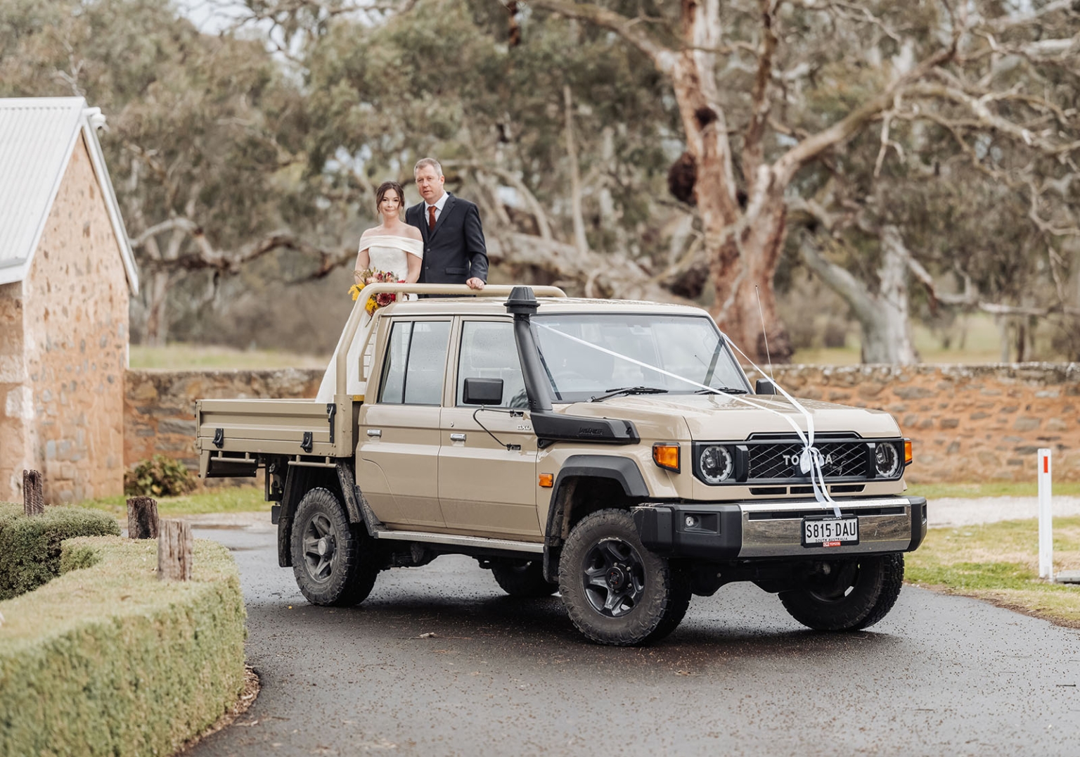 keyneton soldier's memorial hall wedding - lara & simon 28 Lara and Simon standing in the tray of a ribbon-decorated Toyota ute outside Keyneton Soldier's Memorial Hall