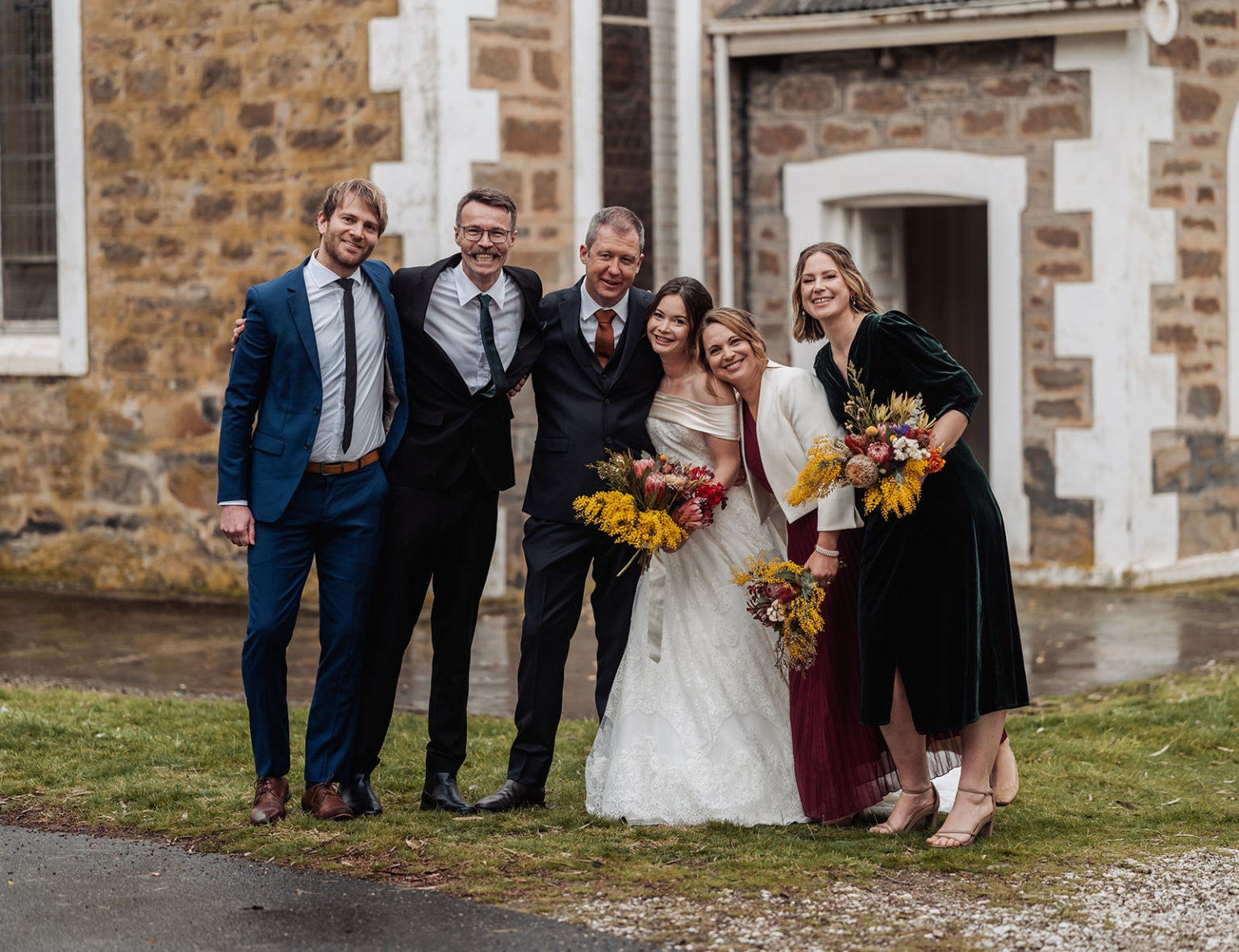 keyneton soldier's memorial hall wedding - lara & simon 22 Lara and Simon smiling with four wedding party members outside the stone church beside Keyneton Soldier's Memorial Hall