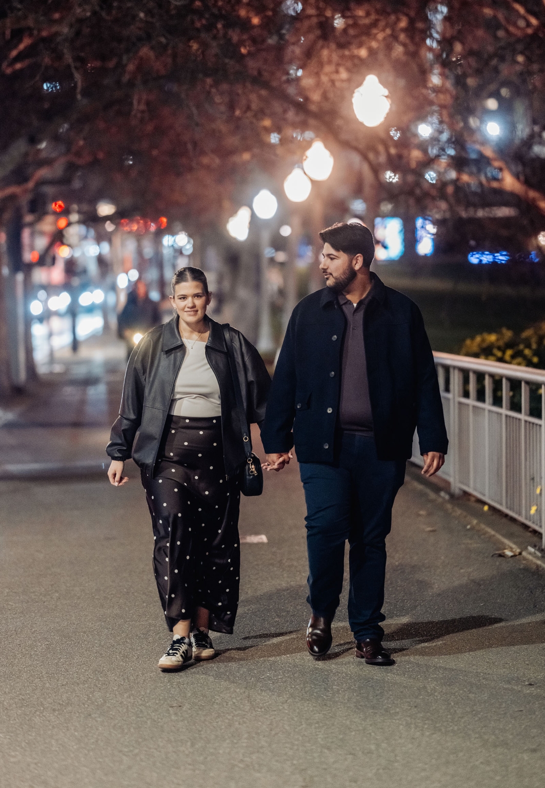 elder park rotunda proposal - lauren & enrique 12 Lauren and Enrique walking hand in hand beneath streetlights near Elder Park in Adelaide at night