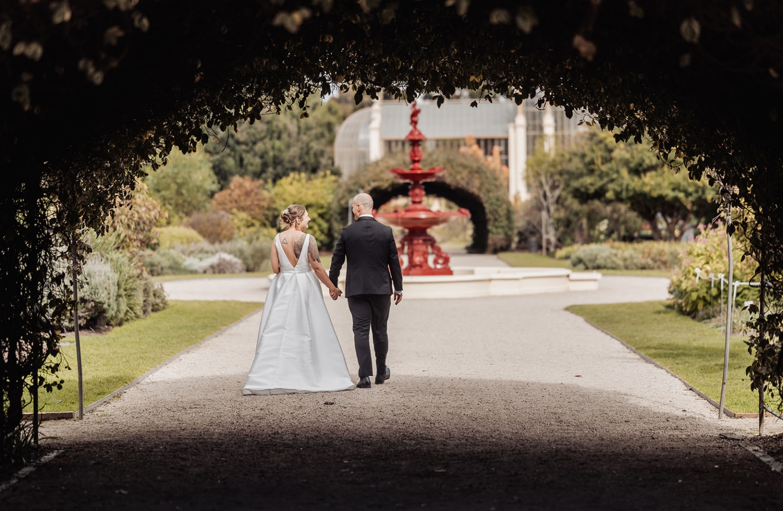 marriage registration office wedding - mia & roberto 67 Mia and Roberto walking hand in hand towards a red fountain in Adelaide Botanic Garden