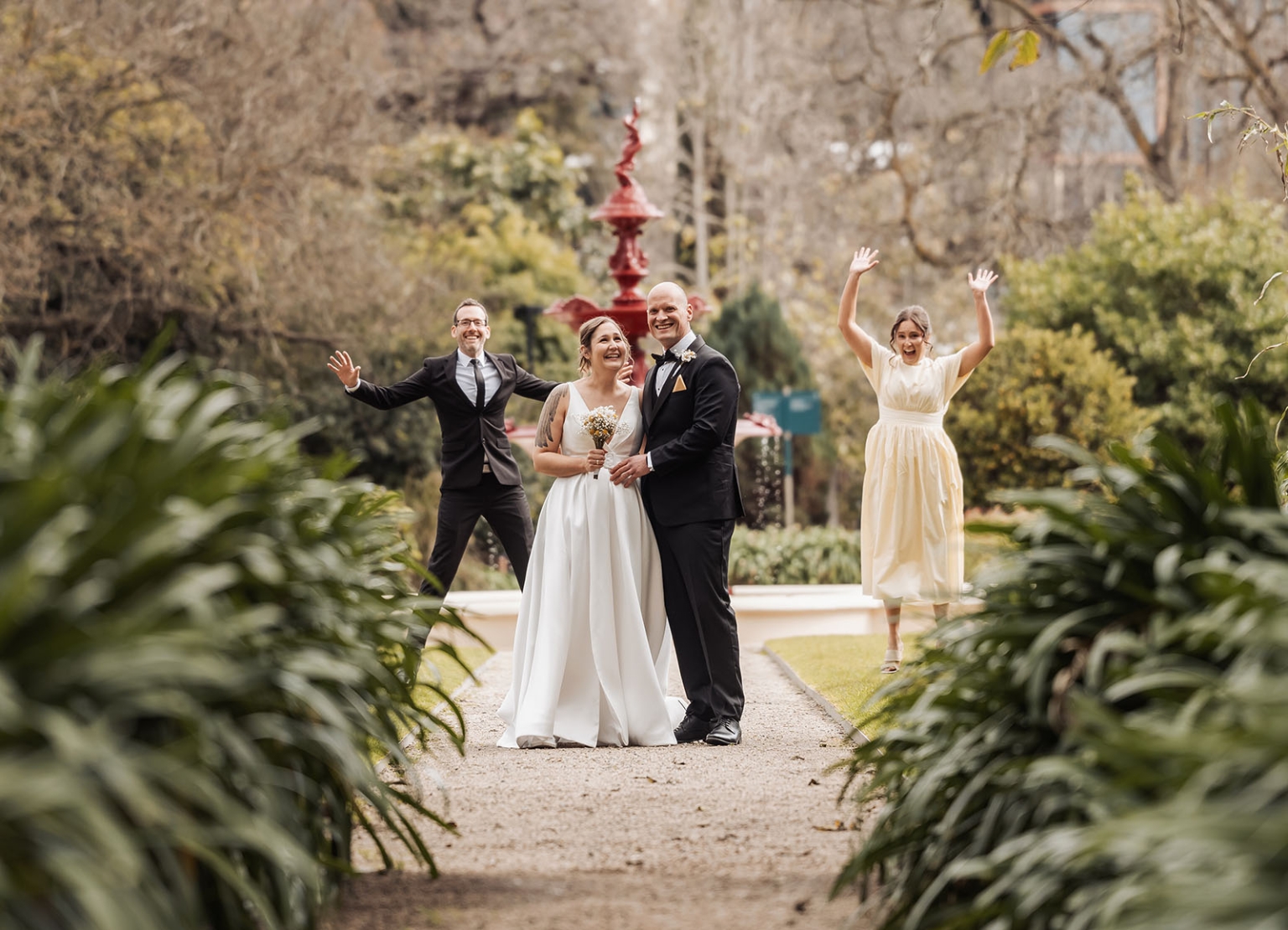 marriage registration office wedding - mia & roberto 68 Mia and Roberto smiling together on a garden path with two wedding guests raising their arms behind them