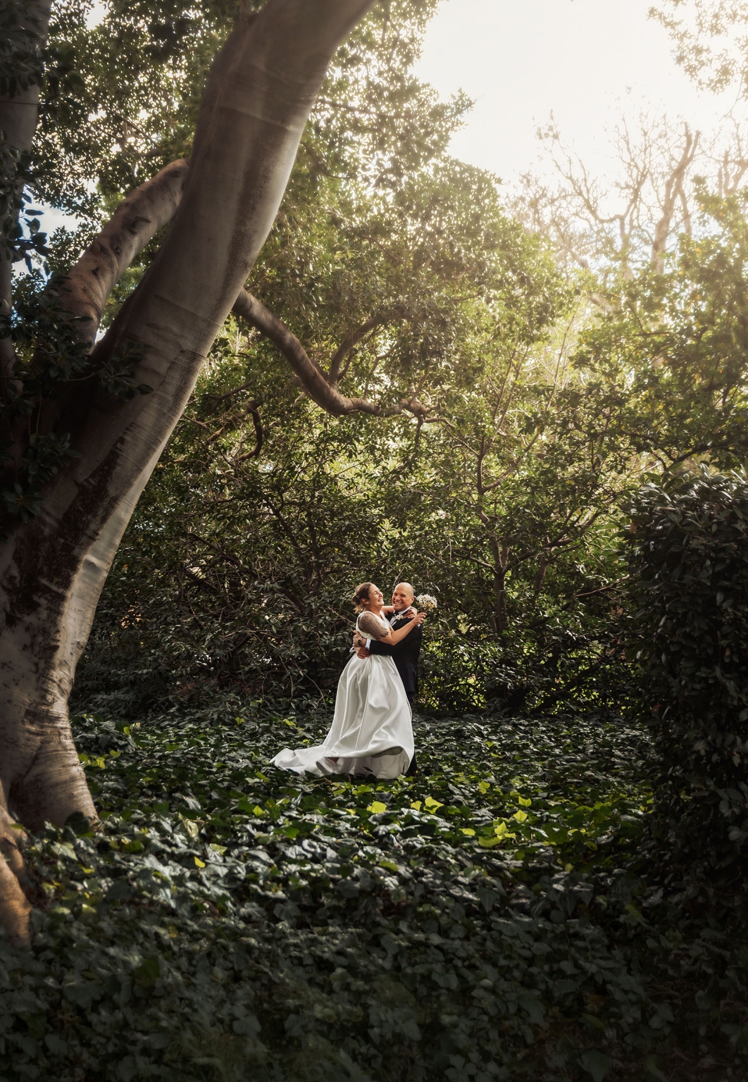 marriage registration office wedding - mia & roberto 76 Mia and Roberto embracing beneath a towering Moreton Bay fig tree in Adelaide Botanic Park