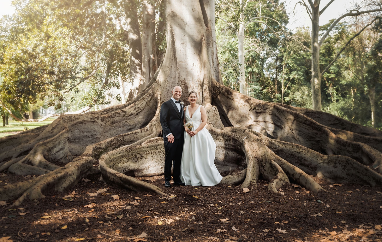marriage registration office wedding - mia & roberto 57 Mia and Roberto in wedding attire standing among the sprawling roots of a Moreton Bay fig tree in Adelaide Botanic Park.