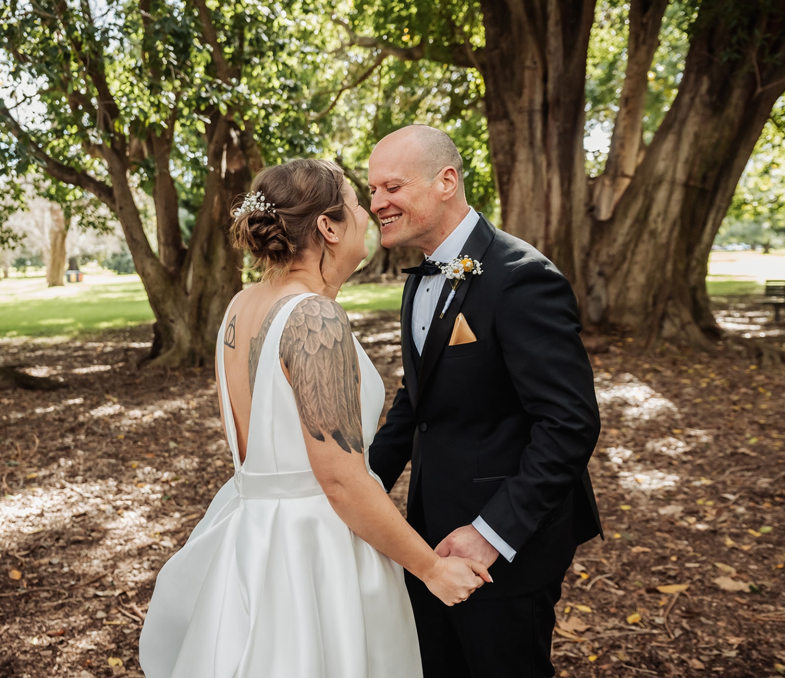 marriage registration office wedding - mia & roberto 52 Mia and Roberto holding hands and smiling beneath large fig trees in Adelaide Botanic Park