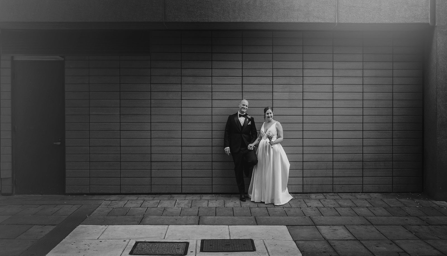 marriage registration office wedding - mia & roberto 97 Mia and Roberto holding hands in wedding attire against a large tiled city wall