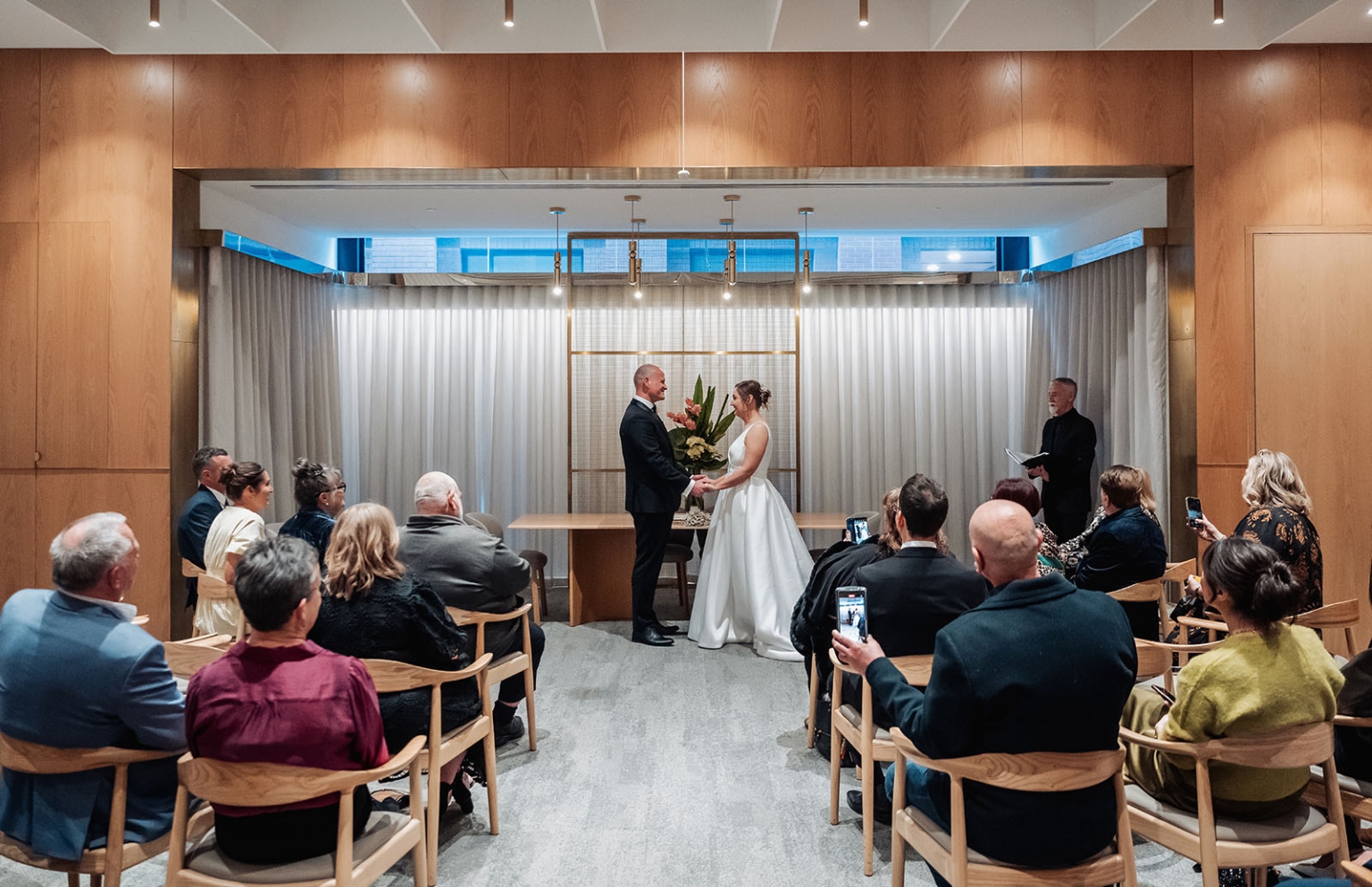 marriage registration office wedding - mia & roberto 89 Mia and Roberto holding hands during their wedding ceremony as guests watch at the Adelaide Marriage and Registration Office