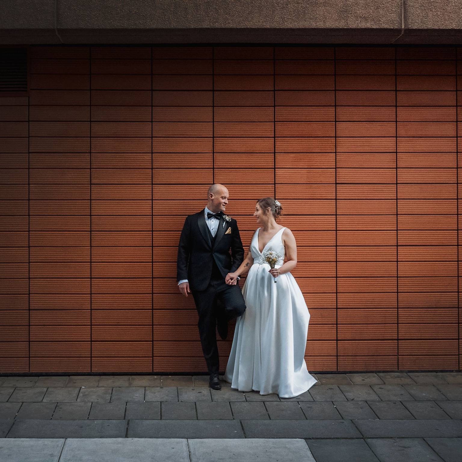 marriage registration office wedding - mia & roberto 96 Mia and Roberto holding hands in wedding attire beside a large timber-panelled wall