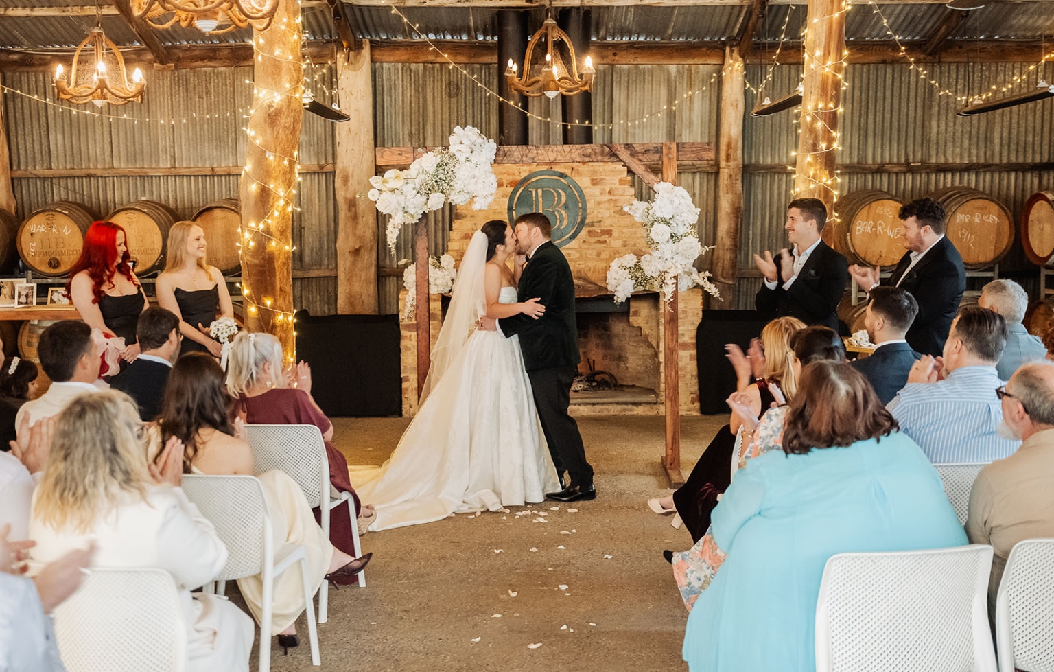 Carley and Corey kiss during their wedding ceremony as guests applaud in the rustic Barristers Block venue.