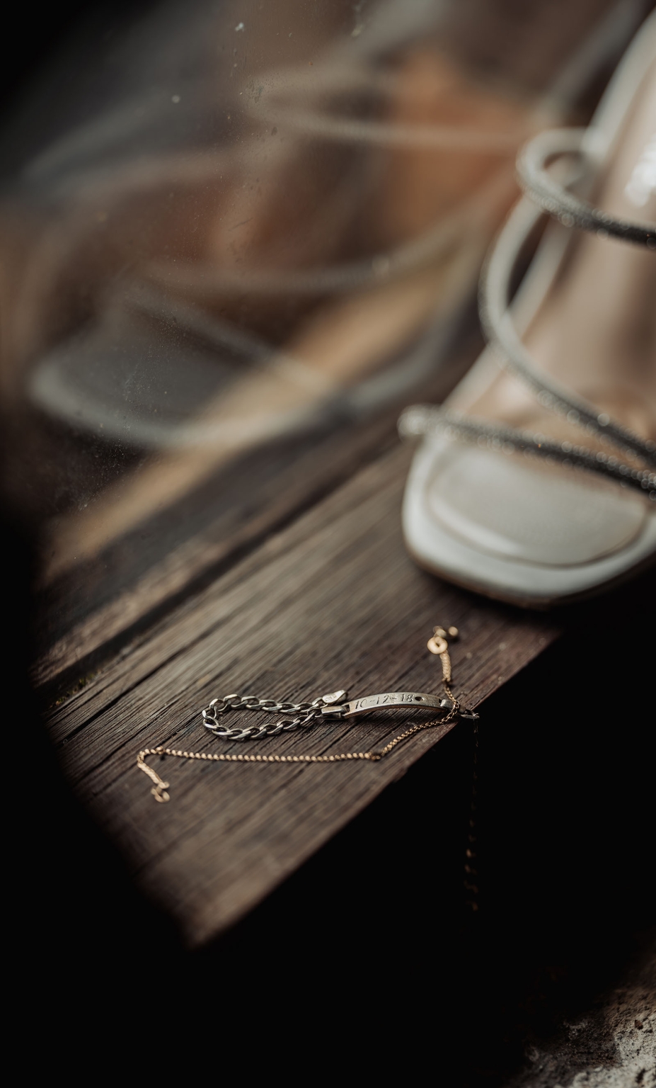 White lace-up bridal heels and delicate jewellery arranged on a rustic wooden windowsill