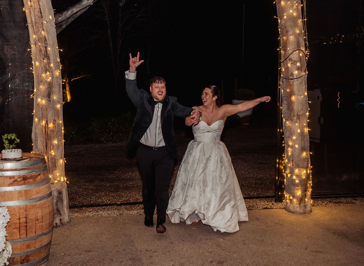 Carley and Corey enter their wedding reception holding hands beneath fairy-lit timber posts at Barristers Block