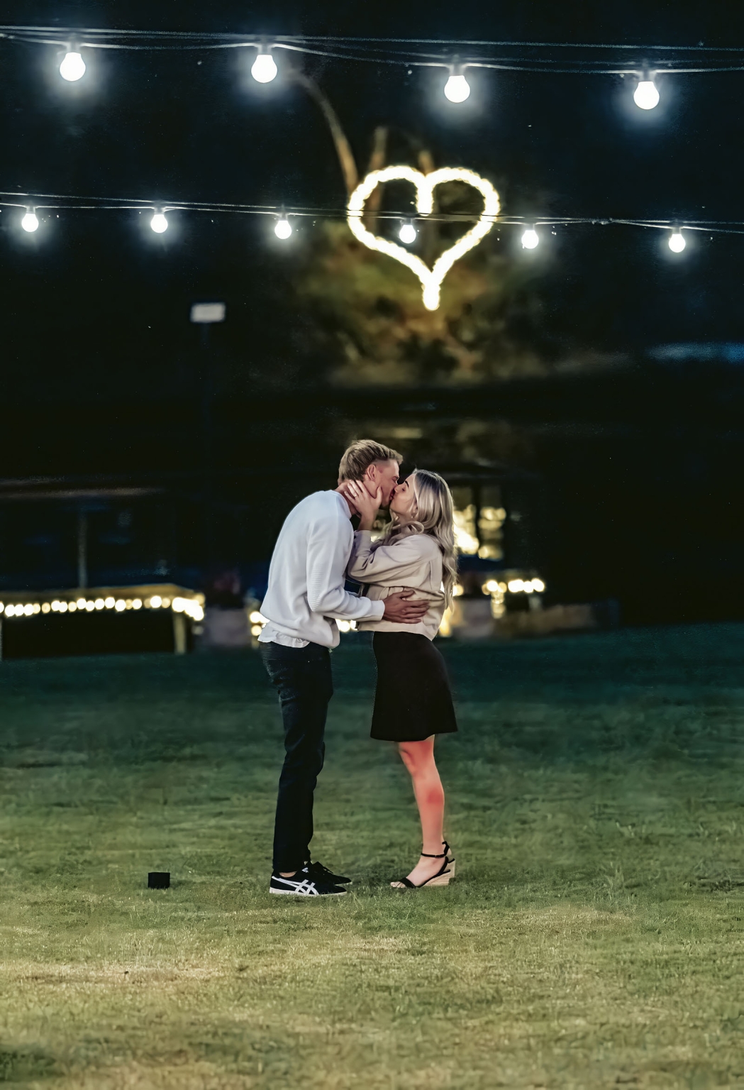 tiny house on the prairie proposal - kyle & bianca 6 Kyle and Bianca kissing beneath string lights and a glowing heart at Tiny House on the Prairie.