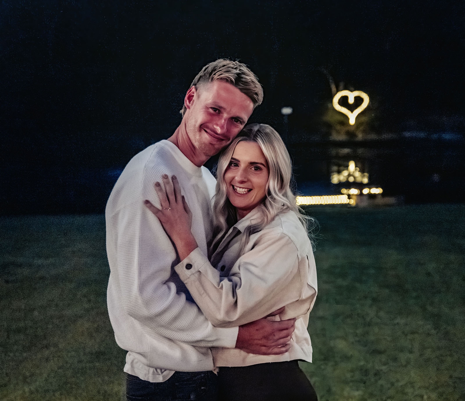 tiny house on the prairie proposal - kyle & bianca 8 Kyle and Bianca embracing and smiling outdoors at night beneath a glowing heart-shaped light