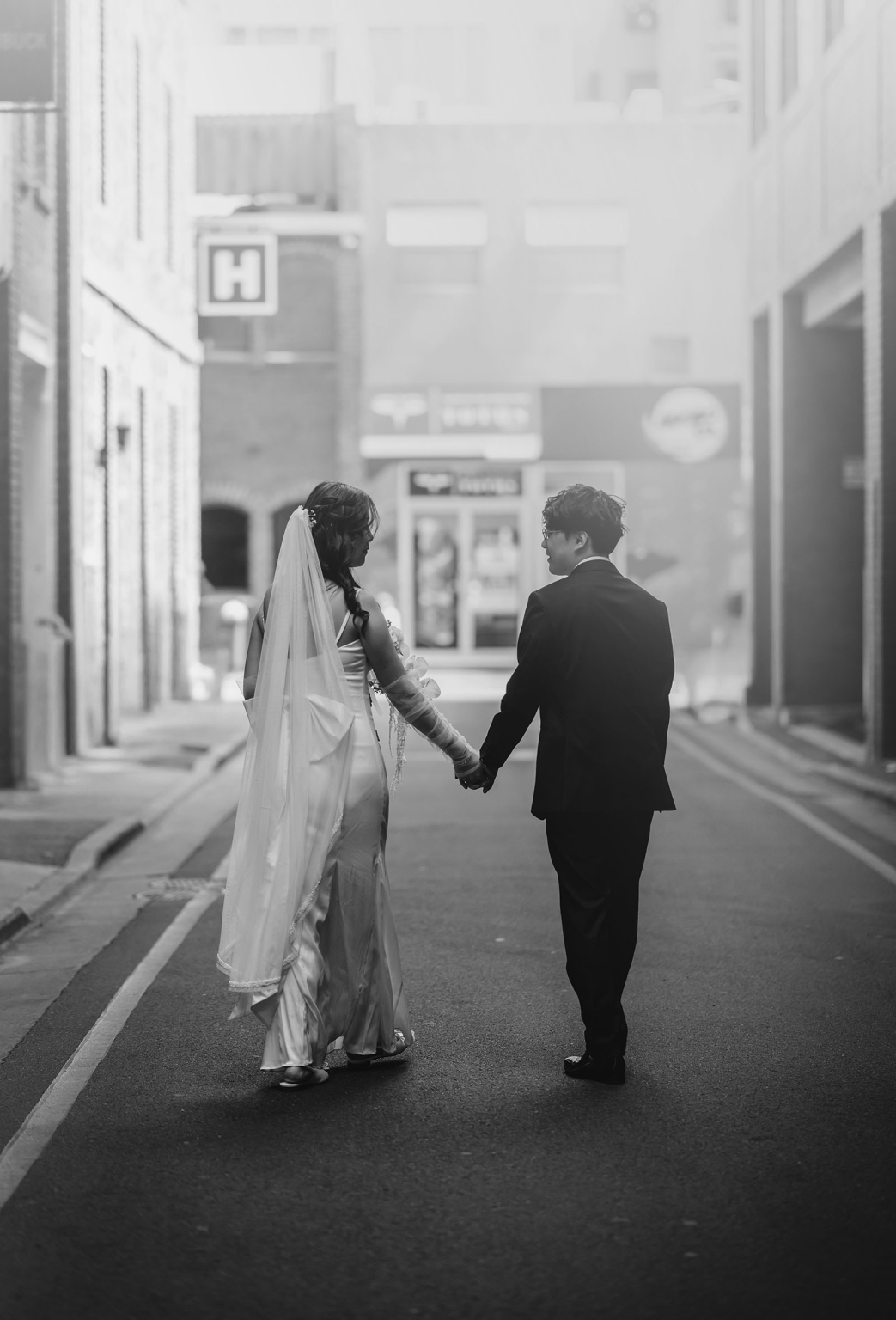 marriage rego office wedding – teri & thomas 16 Teri and Thomas holding hands as they walk along a quiet city street after their wedding ceremony