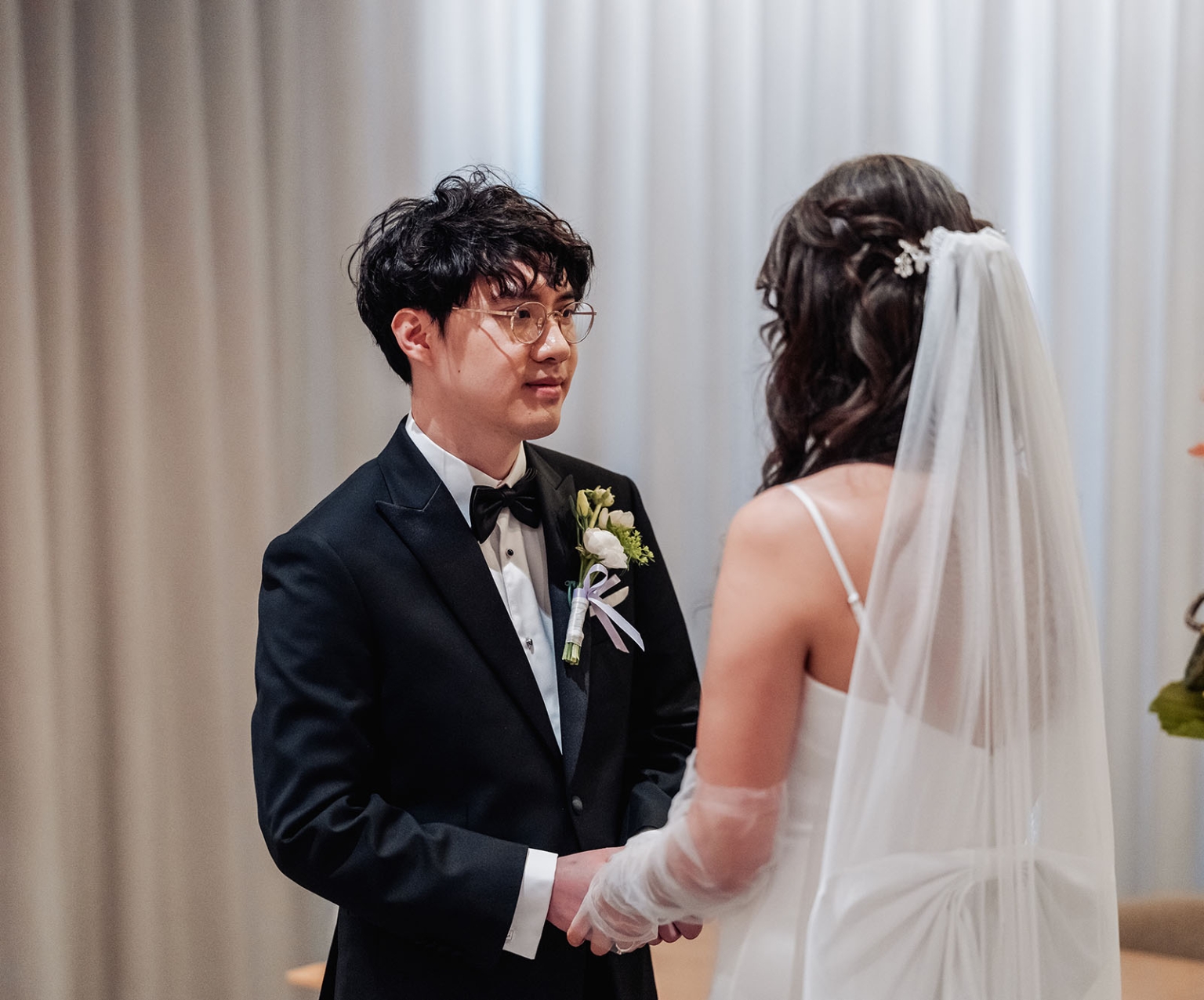 marriage rego office wedding – teri & thomas 3 Thomas in a black tuxedo holds hands with Teri in her wedding dress and veil during their ceremony.